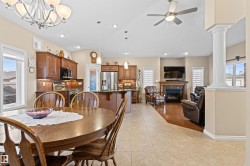 Dining space with healthy amount of natural light, lofted ceiling, a fireplace, light tile patterned flooring, and a chandelier - 