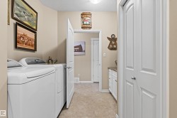 Washroom with a textured ceiling, washing machine and dryer, and light tile patterned flooring - 