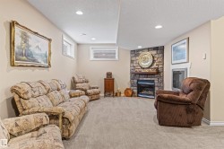 Carpeted living area featuring a stone fireplace, a textured ceiling, and recessed lighting - 