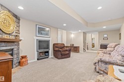 Living room with light carpet, recessed lighting, a stone fireplace, a textured ceiling, and stairway - 