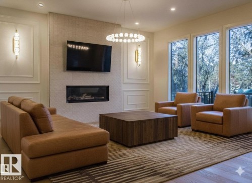 Living area with wood finished floors, a large fireplace, a decorative wall, and recessed lighting. Room has Been Virtually Staged - 12304 39 Avenue, Edmonton, AB 