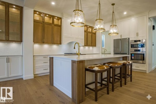 Kitchen with light wood-type flooring, tasteful backsplash, two tone color scheme, a kitchen breakfast bar, and glass fronted cabinets - 12304 39 Avenue, Edmonton, AB 
