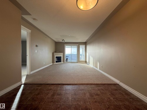 Unfurnished living room featuring a glass covered fireplace and dark carpet - 423 99 Westerra Manor, Stony Plain, AB - Indoor Photo Showing Other Room