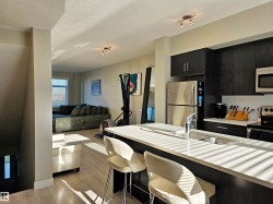 Kitchen featuring dark cabinetry, stainless steel appliances, light wood finished floors, a breakfast bar, and open floor plan - 