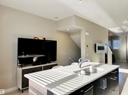 Kitchen with light wood-style flooring, dark cabinets, a kitchen island with sink, open floor plan, and modern cabinets - 