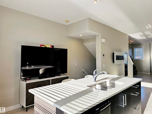 Kitchen with light wood-style flooring, dark cabinets, a kitchen island with sink, open floor plan, and modern cabinets - 83 600 Bellerose Drive, St. Albert, AB - Indoor Photo Showing Other Room