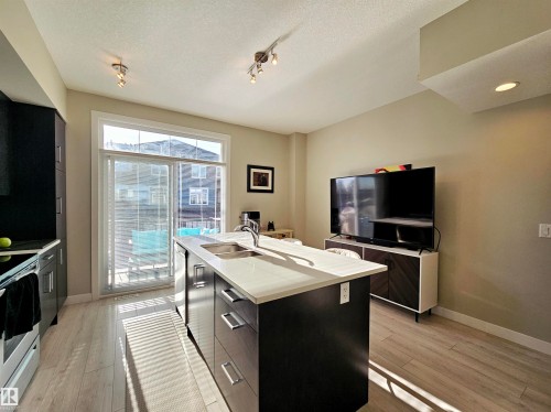 Kitchen with modern cabinets, stainless steel appliances, a kitchen island with sink, rail lighting, and light wood finished floors - 83 600 Bellerose Drive, St. Albert, AB - Indoor Photo Showing Kitchen With Double Sink