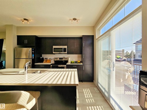 Kitchen with dark cabinets, stainless steel appliances, tasteful backsplash, heating unit, and a breakfast bar area - 83 600 Bellerose Drive, St. Albert, AB - Indoor Photo Showing Kitchen With Stainless Steel Kitchen