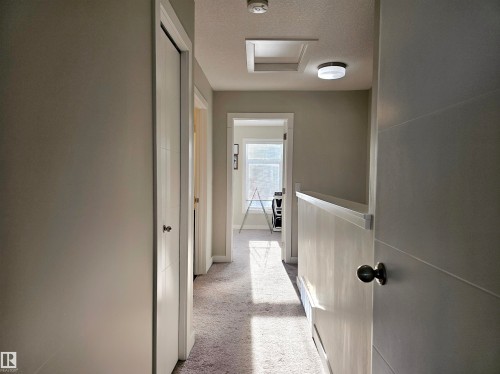 Hall with light colored carpet, a textured ceiling, and attic access - 83 600 Bellerose Drive, St. Albert, AB - Indoor Photo Showing Other Room