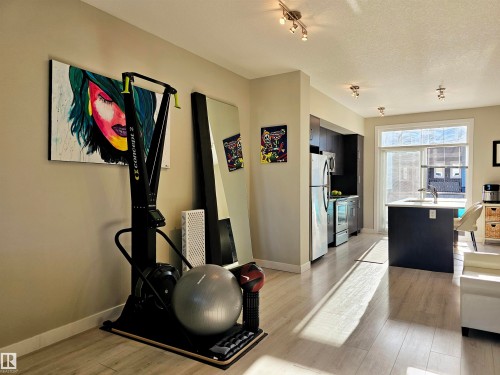 Kitchen with an island with sink, light countertops, light wood finished floors, dark cabinetry, and stainless steel appliances - 83 600 Bellerose Drive, St. Albert, AB - Indoor