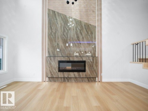 Unfurnished living room with a glass covered fireplace and light wood-type flooring - 15419 20 Street, Edmonton, AB - Indoor With Fireplace
