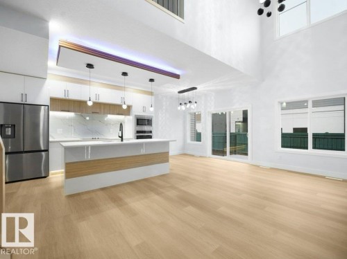 Unfurnished living room featuring light wood-type flooring, healthy amount of natural light, and a towering ceiling - 15419 20 Street, Edmonton, AB - Indoor Photo Showing Kitchen With Stainless Steel Kitchen