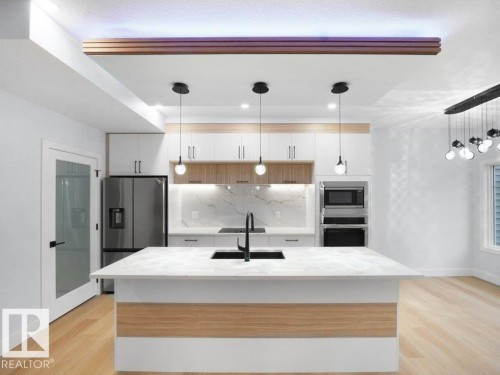 Kitchen with decorative light fixtures, tasteful backsplash, appliances with stainless steel finishes, a kitchen island with sink, and light wood-style flooring - 15419 20 Street, Edmonton, AB - Indoor Photo Showing Kitchen With Stainless Steel Kitchen With Upgraded Kitchen