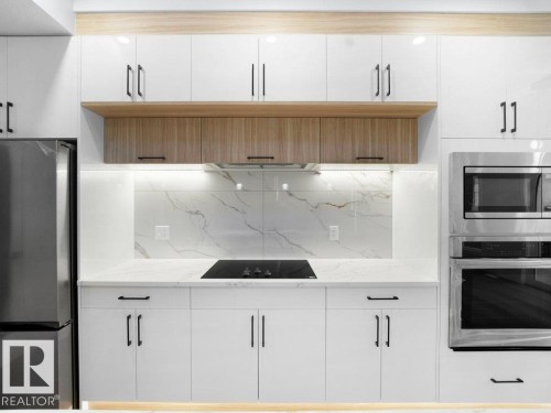 Kitchen featuring appliances with stainless steel finishes, tasteful backsplash, light stone countertops, and white cabinetry - 15419 20 Street, Edmonton, AB - Indoor Photo Showing Kitchen