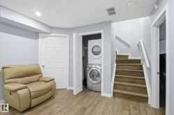 Laundry room with light wood-style flooring, estacked washer and dryer, and recessed lighting - 