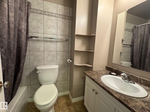 Full bathroom featuring vanity, dark tile patterned floors, tile walls, and shower / bath combination with curtain - 4707 53 Street, Athabasca Town, AB - Indoor Photo Showing Bathroom