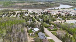 Residential properties situated among mature trees, with paved roads and a visible river - 