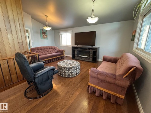 Living room with lofted ceiling, wood finished floors, and a fireplace - 4707 53 Street, Athabasca Town, AB - Indoor Photo Showing Living Room