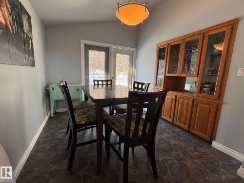 Dining space featuring dark stone finish floors, lofted ceiling, and radiator heating unit - 4707 53 Street, Athabasca Town, AB - Indoor Photo Showing Dining Room