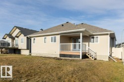 Rear view of house featuring a yard, a deck, and a shingled roof - 