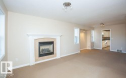 Unfurnished living room featuring a tiled fireplace and carpet floors - 