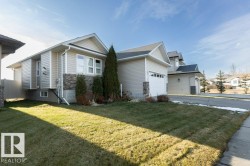 View of side of property with a yard, an attached garage, stone siding, and driveway - 