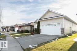 View of front of property with concrete driveway, stone siding, an attached garage, and a front lawn - 