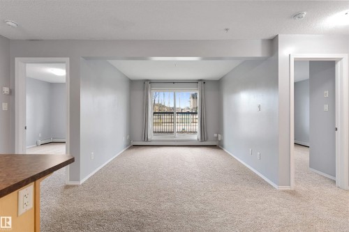 Empty room with light colored carpet, a textured ceiling, and baseboard heating - 111 5951 165 Avenue, Edmonton, AB - Indoor Photo Showing Other Room
