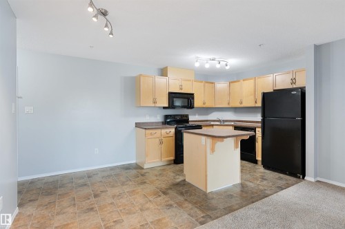 Kitchen with black appliances, stone finish floors, and light brown cabinets - 111 5951 165 Avenue, Edmonton, AB - Indoor Photo Showing Kitchen