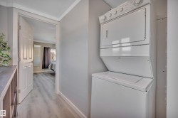 Laundry area with light wood finished floors, stacked washer and clothes dryer, and crown molding - 