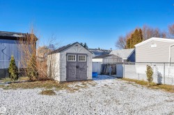 Snow covered structure with a fenced backyard and a shed - 