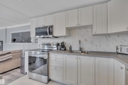 Kitchen featuring stainless steel appliances, decorative backsplash, and white cabinets - 