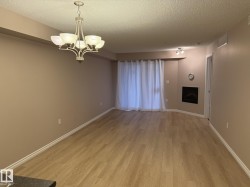 Unfurnished dining area featuring a textured ceiling, a chandelier, light wood finished floors, and a fireplace - 