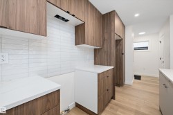 Kitchen featuring brown cabinetry, modern cabinets, light wood finished floors, and light stone counters - 