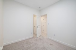 Empty room with light colored carpet and baseboards - 