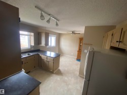 Kitchen with freestanding refrigerator, a peninsula, rail lighting, dark countertops, and a ceiling fan - 