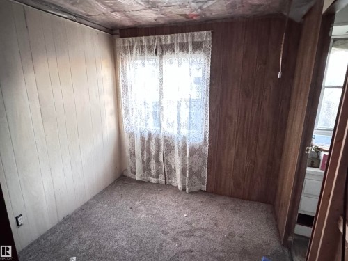 Empty room with wood walls and carpet flooring - 4748 50 St., Vimy, AB - Indoor Photo Showing Other Room