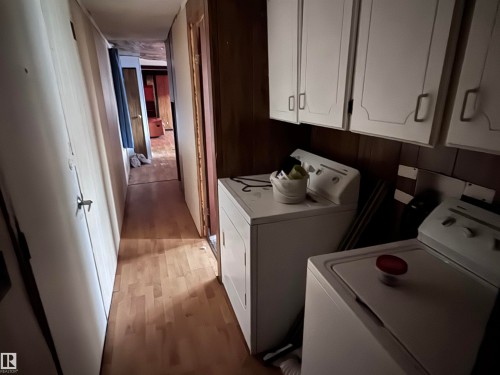 Laundry area with light wood-style flooring, cabinet space, separate washer and dryer, and wood walls - 4748 50 St., Vimy, AB - Indoor Photo Showing Laundry Room