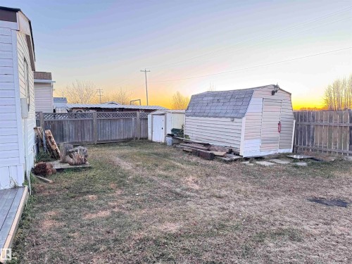 Yard at dusk featuring a shed and a fenced backyard - 4748 50 St., Vimy, AB - Outdoor