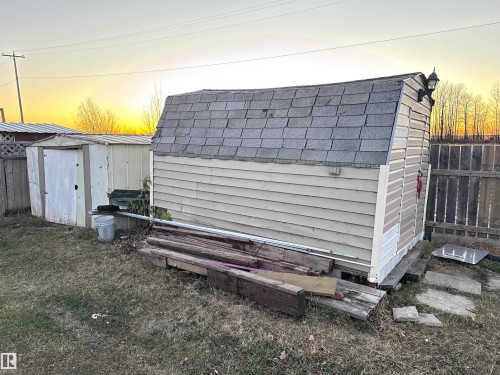 Outdoor structure at dusk with a storage shed and a fenced backyard - 4748 50 St., Vimy, AB - Outdoor