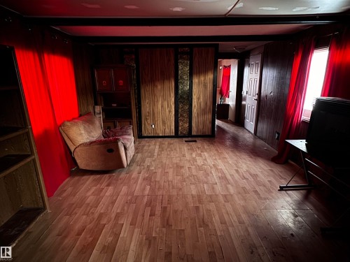 Sitting room with light wood finished floors and wood walls - 4748 50 St., Vimy, AB - Indoor Photo Showing Other Room