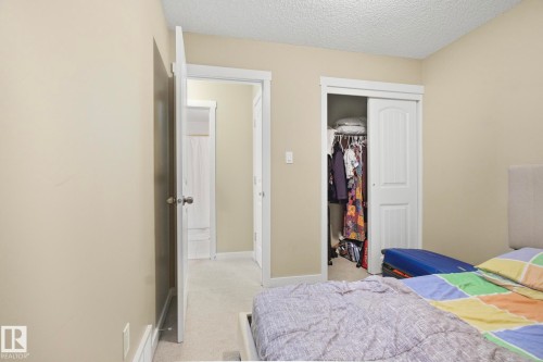Bedroom with light colored carpet, a textured ceiling, and a closet - 30 6075 Schonsee Way, Edmonton, AB - Indoor Photo Showing Bedroom