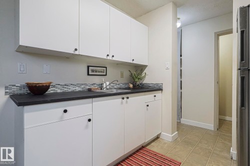 Bar area with dark countertops, white cabinetry, light tile patterned floors, and freestanding refrigerator - 51 Belmead Gardens, Edmonton, AB - Indoor Photo Showing Kitchen With Double Sink