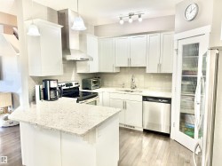 Kitchen featuring a peninsula, backsplash, stainless steel appliances, and white cabinets - 