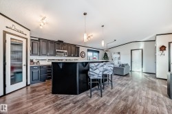 Kitchen featuring a breakfast bar area, open floor plan, decorative light fixtures, dark wood-style flooring, and vaulted ceiling - 