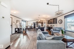 Living room with ornamental molding, light wood-style flooring, and vaulted ceiling - 
