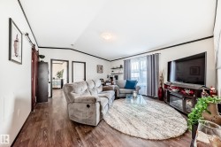 Living area with crown molding, vaulted ceiling, and dark wood-style flooring - 