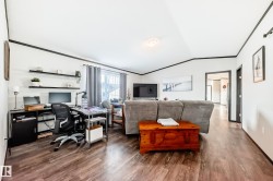 Living area featuring a chandelier, dark wood-type flooring, lofted ceiling, and crown molding - 