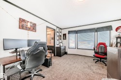 Bedroom with a desk, multiple windows, and light colored carpet - 