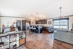 Living room featuring a chandelier, crown molding, vaulted ceiling, and light wood-style flooring - 